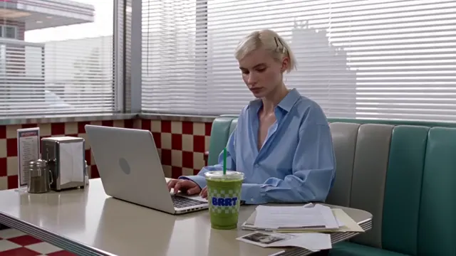 Woman using a laptop at a desk with a diner-style background