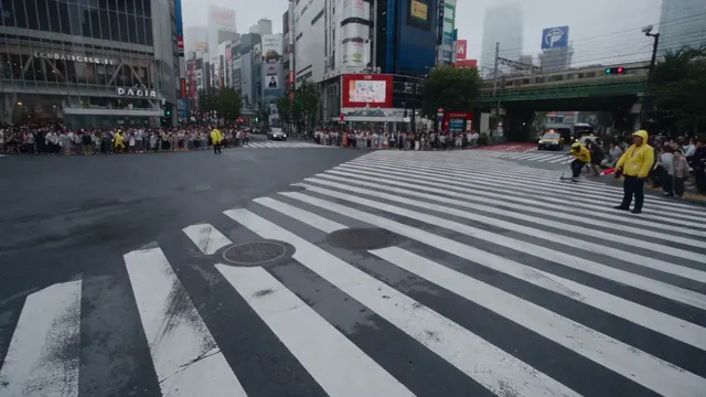 Pedestrians at a wide city crossing surrounded by buildings