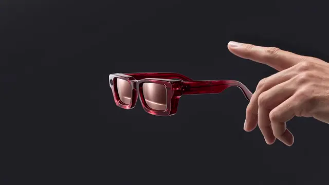 Red-framed glasses beside an outstretched hand on a dark background