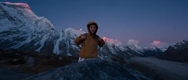 Traveler in an orange jacket against snowy mountain peaks