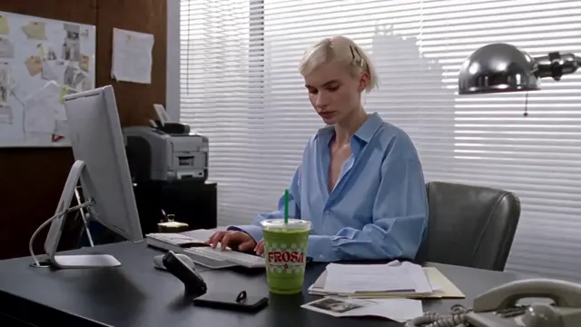 Woman at an office desk beside a green takeaway drink